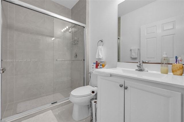 bathroom with tile patterned floors, a shower with shower door, toilet, and vanity