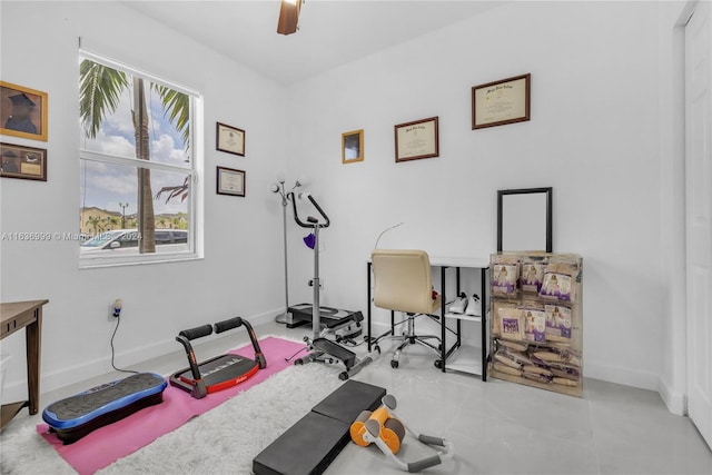 exercise area with light tile patterned floors and ceiling fan