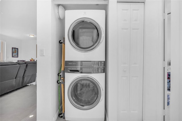 laundry room with light tile patterned floors and stacked washer / drying machine