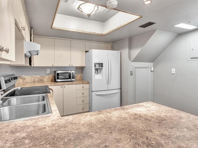 kitchen with exhaust hood, a raised ceiling, sink, appliances with stainless steel finishes, and cream cabinetry