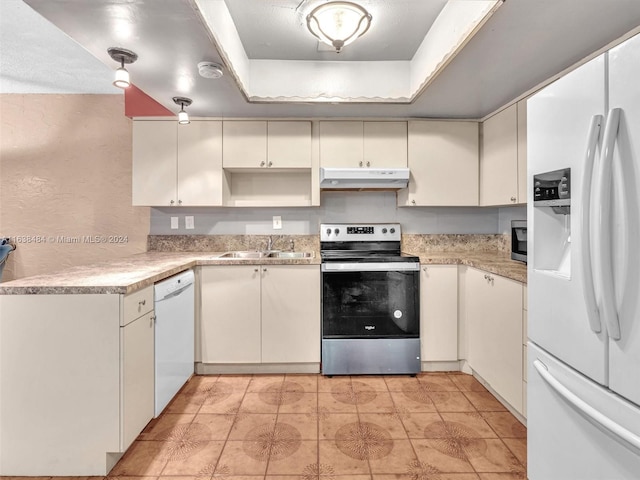 kitchen with a tray ceiling, white cabinetry, sink, and appliances with stainless steel finishes