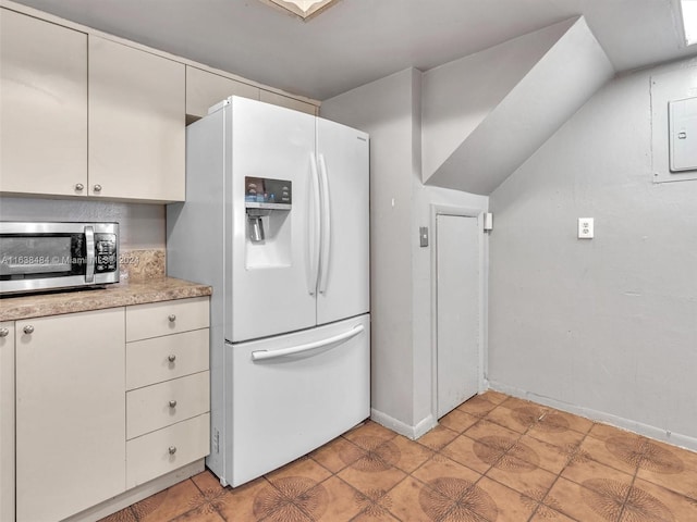 kitchen featuring white cabinets, light tile patterned floors, and white fridge with ice dispenser