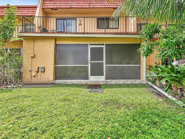 rear view of property featuring a sunroom and a lawn