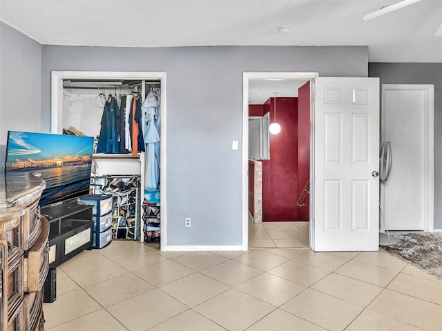 tiled bedroom featuring a textured ceiling, a closet, and ceiling fan