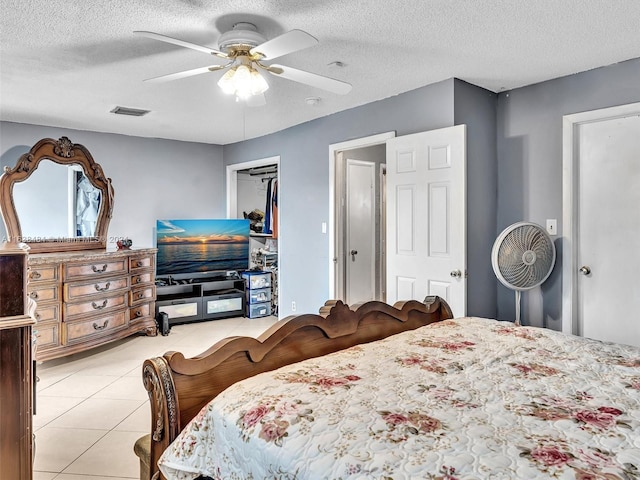 tiled bedroom with ceiling fan, a closet, and a textured ceiling