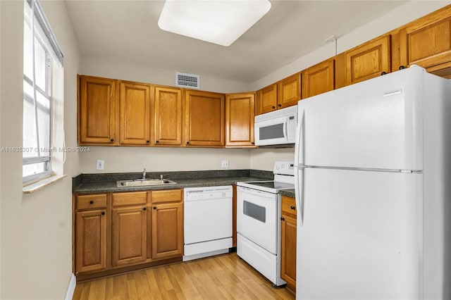 kitchen with sink, light wood-type flooring, and white appliances