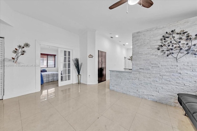 tiled living room with ceiling fan and french doors