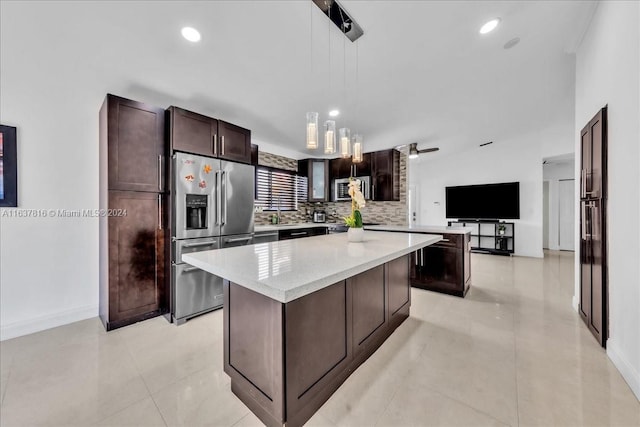 kitchen with light tile patterned floors, hanging light fixtures, high end fridge, backsplash, and a center island