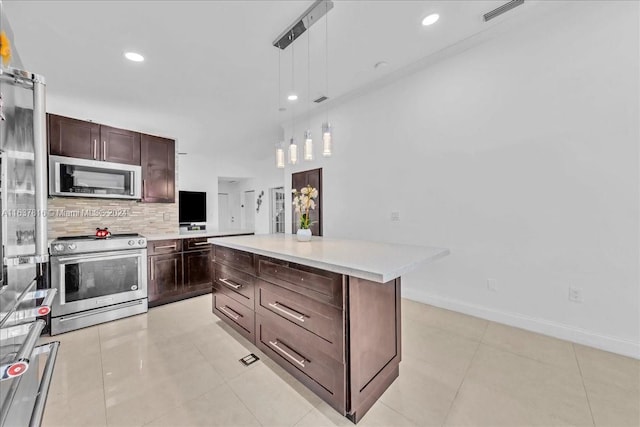 kitchen featuring light tile patterned floors, appliances with stainless steel finishes, hanging light fixtures, and backsplash