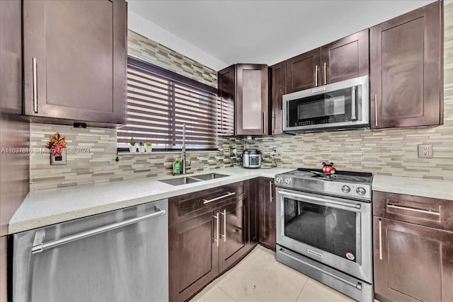 kitchen featuring stainless steel appliances, light tile patterned floors, dark brown cabinets, backsplash, and sink