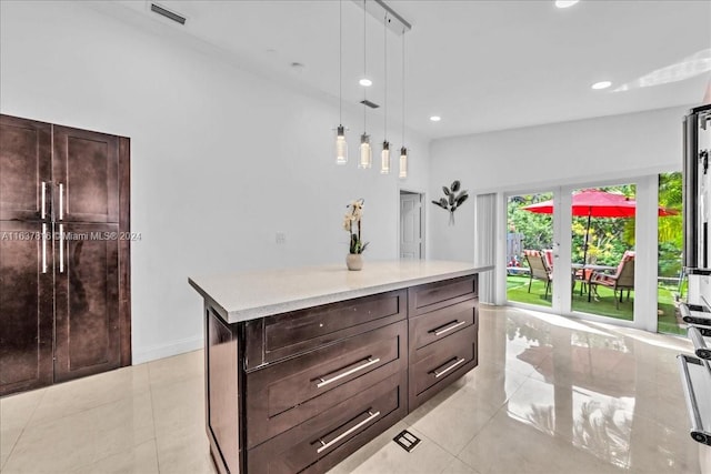 kitchen featuring dark brown cabinets, a center island, light tile patterned floors, and hanging light fixtures