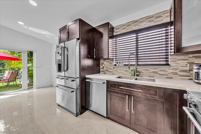 kitchen featuring stainless steel appliances, backsplash, sink, light tile patterned flooring, and dark brown cabinetry