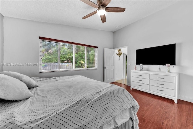 bedroom featuring ceiling fan, wood-type flooring, a textured ceiling, and lofted ceiling