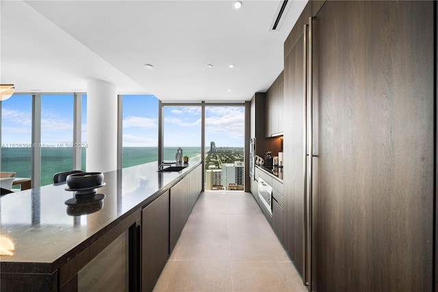 kitchen featuring light tile patterned flooring, a water view, sink, and plenty of natural light