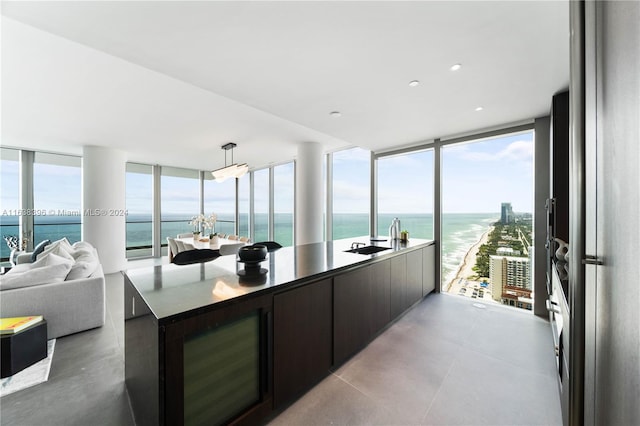 kitchen featuring dark brown cabinets, floor to ceiling windows, a water view, and decorative light fixtures