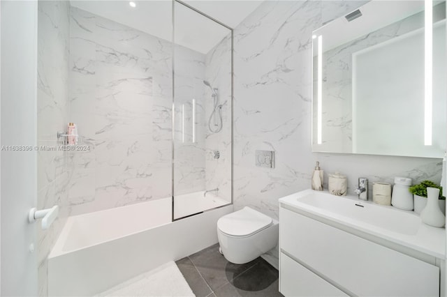 full bathroom with toilet, tile walls, tile patterned flooring, tiled shower / bath combo, and vanity