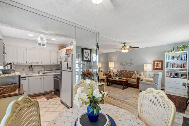 dining space with ceiling fan, sink, and a textured ceiling