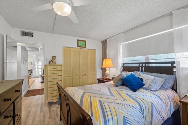 bedroom with ceiling fan, light wood-type flooring, a textured ceiling, and a closet