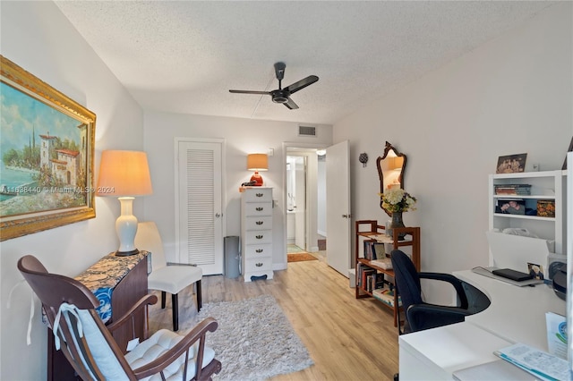 home office featuring ceiling fan, light hardwood / wood-style floors, and a textured ceiling