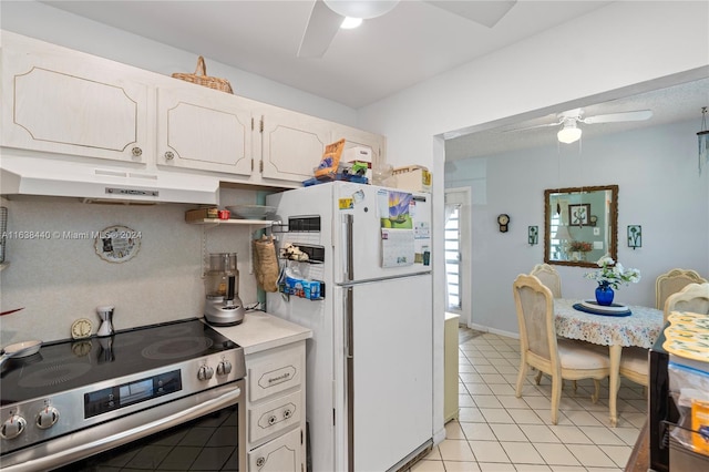 kitchen with stainless steel range with electric stovetop, white refrigerator, decorative backsplash, light tile patterned flooring, and white cabinetry