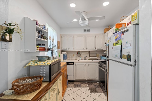 kitchen featuring ceiling fan, sink, stainless steel appliances, light tile patterned flooring, and white cabinets