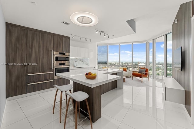 kitchen featuring light tile patterned floors, stainless steel double oven, visible vents, light countertops, and decorative backsplash