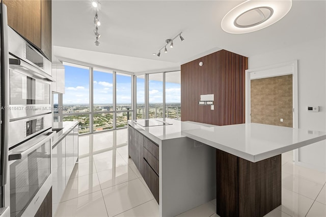 kitchen featuring a kitchen island, modern cabinets, black electric cooktop, light countertops, and floor to ceiling windows