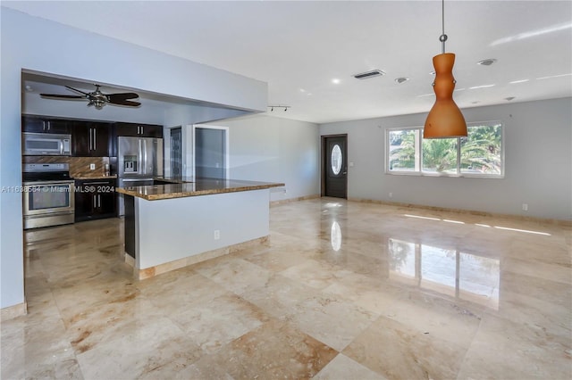 kitchen with hanging light fixtures, ceiling fan, stainless steel appliances, dark stone countertops, and decorative backsplash