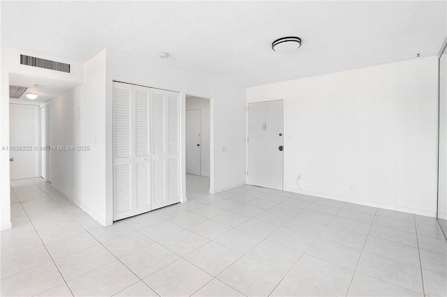 empty room with light tile patterned floors and a textured ceiling