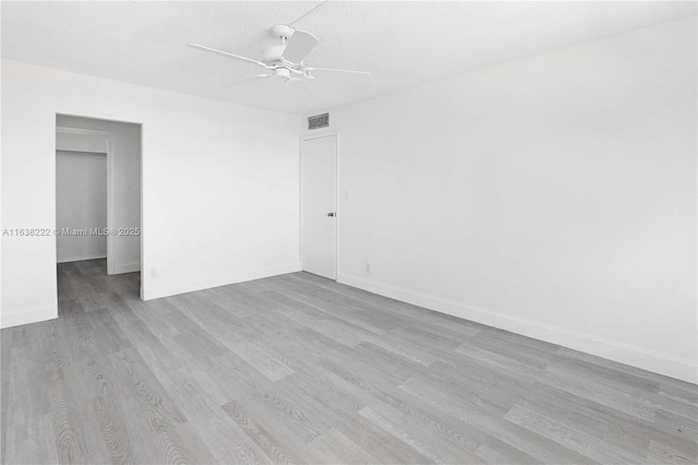 unfurnished room featuring ceiling fan, light wood-type flooring, and a textured ceiling