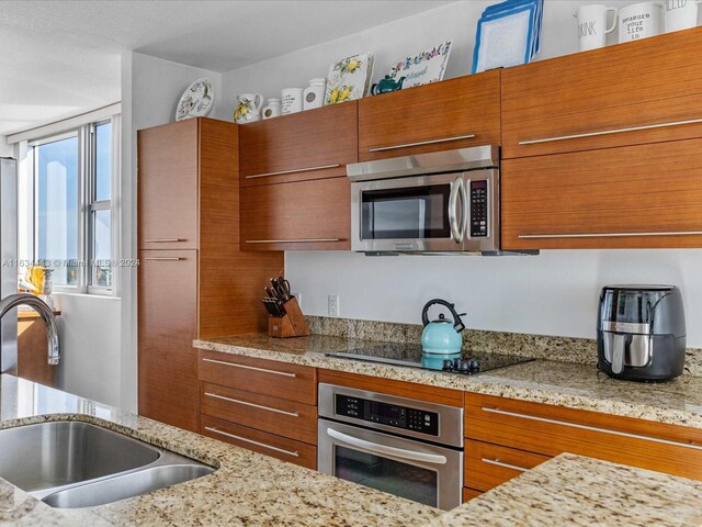 kitchen with light stone counters, stainless steel appliances, and sink