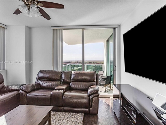 living room featuring ceiling fan, expansive windows, and wood-type flooring