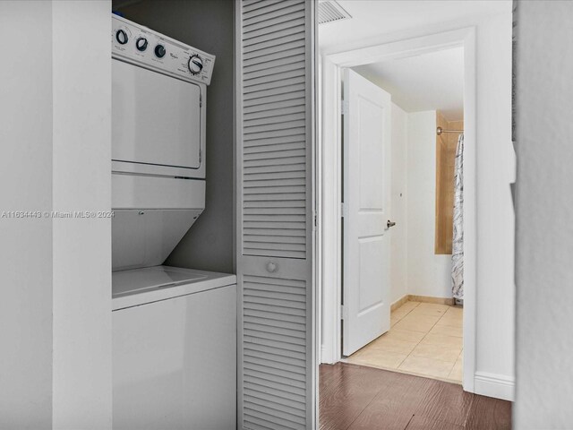 laundry area featuring light wood-type flooring and stacked washer / dryer