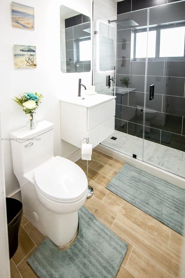 bathroom featuring sink, a shower with door, toilet, and tile patterned flooring