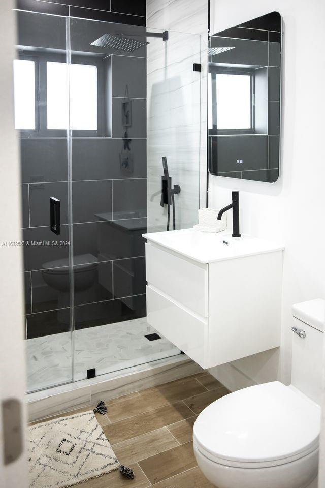 bathroom featuring toilet, a shower with shower door, and a wealth of natural light