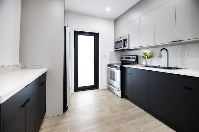 kitchen featuring tasteful backsplash, appliances with stainless steel finishes, sink, and white cabinets