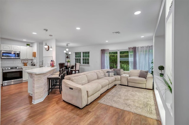 living room with light hardwood / wood-style flooring and a notable chandelier