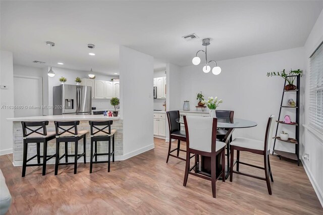 dining space with light hardwood / wood-style flooring and an inviting chandelier