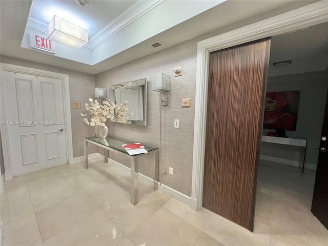 hall with tile patterned flooring, visible vents, baseboards, and ornamental molding