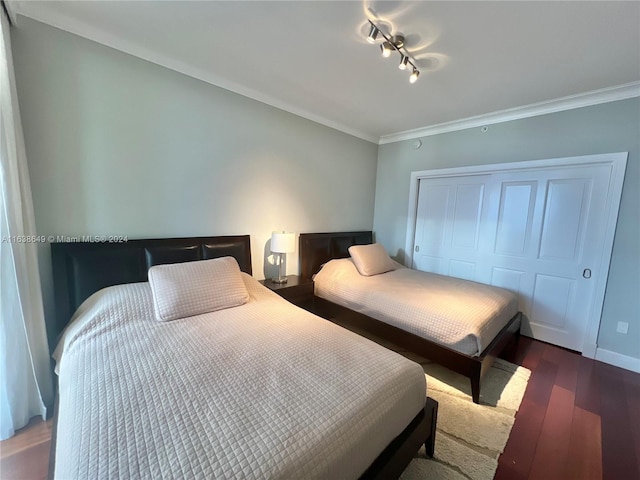 bedroom with a closet, crown molding, baseboards, and wood finished floors