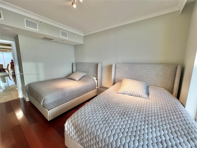 bedroom with visible vents, wood finished floors, and ornamental molding