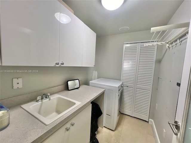 laundry room featuring washing machine and clothes dryer, light tile patterned flooring, cabinet space, and a sink