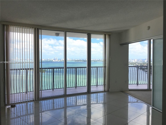 tiled empty room with a textured ceiling and a water view