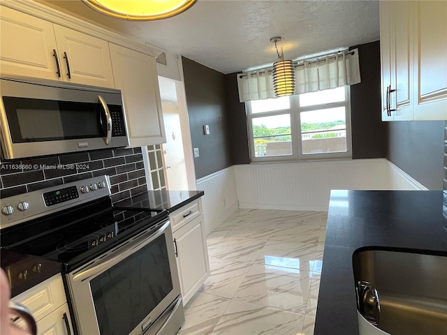 kitchen featuring light tile patterned floors, decorative backsplash, stainless steel appliances, and white cabinets