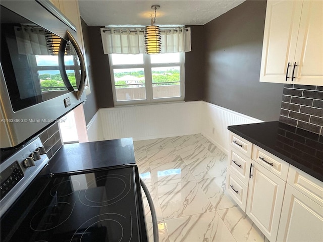 kitchen with decorative backsplash, hanging light fixtures, light tile patterned floors, white cabinets, and stainless steel range with electric cooktop