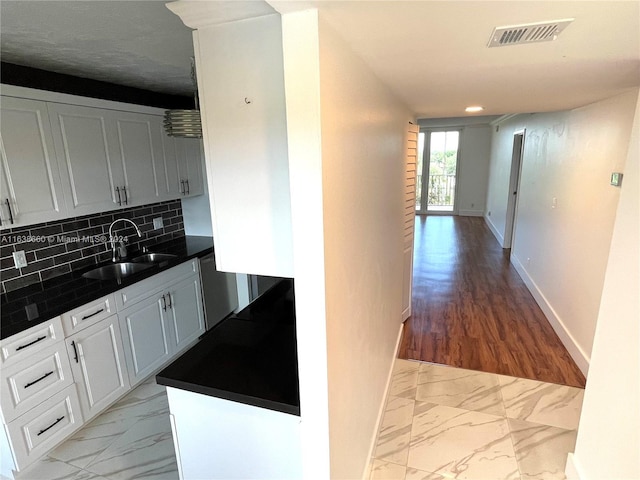 kitchen with marble finish floor, tasteful backsplash, dark countertops, visible vents, and a sink