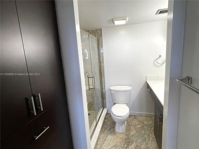 bathroom with toilet, vanity, a shower with shower door, and tile patterned flooring