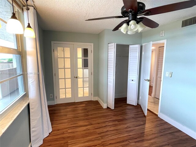 unfurnished bedroom with ceiling fan, a textured ceiling, french doors, and wood-type flooring