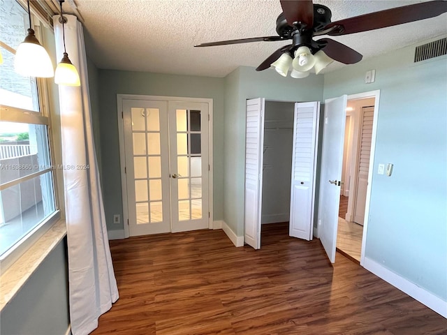 unfurnished bedroom with a textured ceiling, dark wood-type flooring, visible vents, baseboards, and french doors