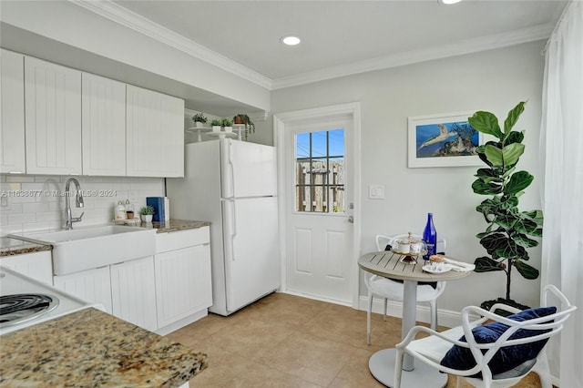 kitchen with tasteful backsplash, white cabinets, crown molding, and freestanding refrigerator